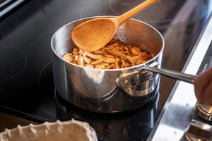cooking spoon in pot of apple filling on stove