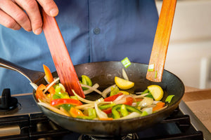 modern hardwood spatulas sauteing in a lodge cast iron pan - Earlywood