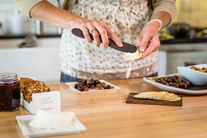wooden butter knife spreading brie on cracker - Earlywood